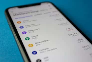 Close-up photo of a smartphone displaying cryptocurrency market data with price listings.
