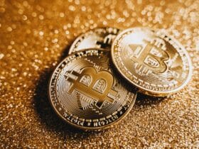 Close-up of shiny bitcoins on a gold glitter background, symbolizing cryptocurrency wealth.
