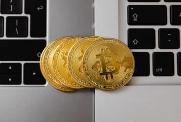 Close-up of Bitcoin coins resting on two laptop keyboards, representing digital currency and technology.