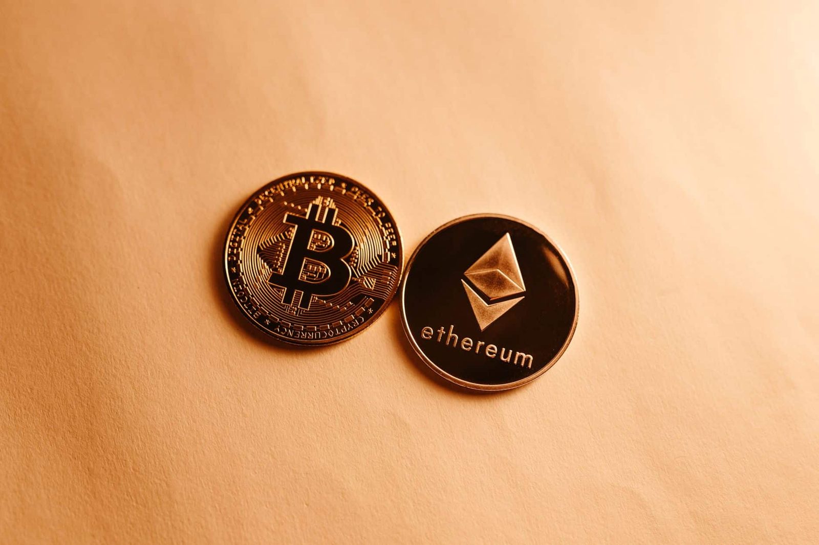 Bitcoin and Ethereum coins depicted on a soft yellow background for cryptocurrency and finance themes.