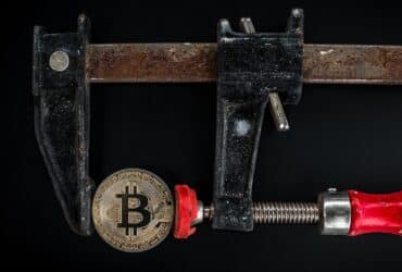 Conceptual image of cryptocurrency represented by a Bitcoin secured in a rusty clamp.