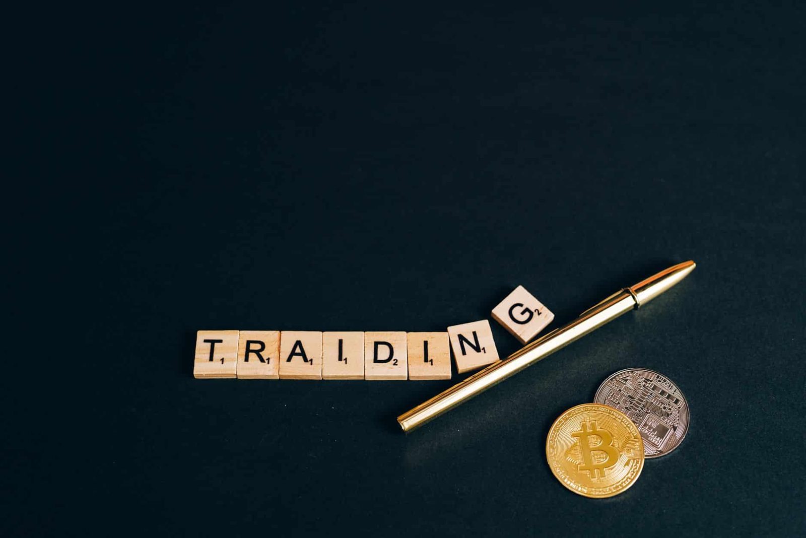 Bitcoin and trading concept shown with coins, pen, and letter tiles on a dark background.