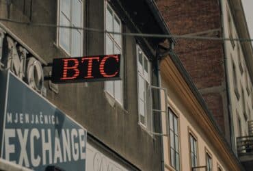 Exterior of a building featuring a prominent BTC and exchange sign, indicating a cryptocurrency location.