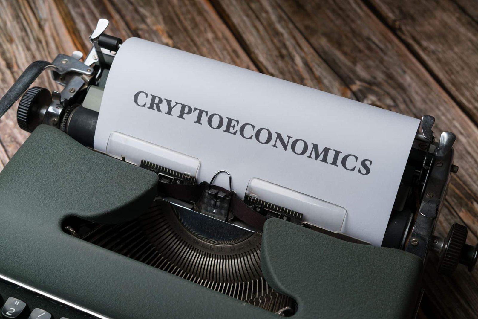 Cryptoeconomics typed on paper using vintage typewriter on wooden background.