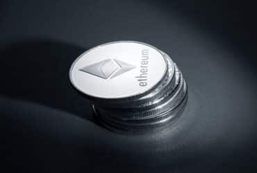 Close-up of stacked Ethereum coins on a dark textured surface, symbolizing modern cryptocurrency.