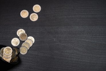 A collection of euro coins scattered on a dark textured surface, with space for text.