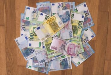 A pile of Euro and Turkish Lira banknotes scattered on a wooden surface, showcasing various denominations.