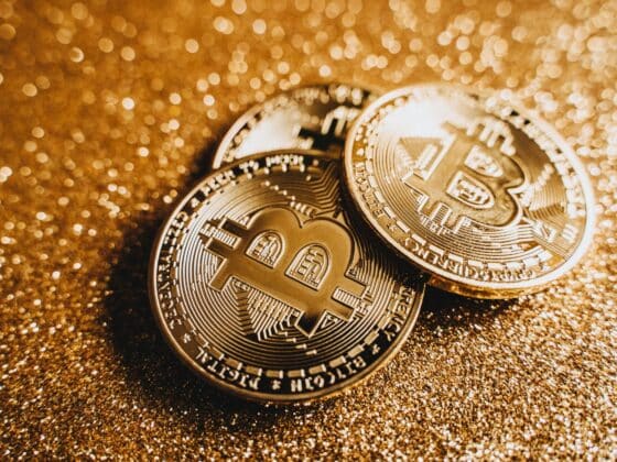 Close-up of shiny bitcoins on a gold glitter background, symbolizing cryptocurrency wealth.