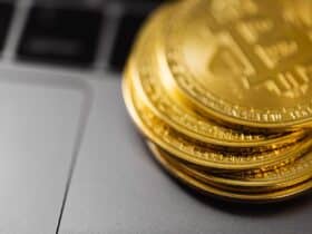 Stack of gold Bitcoin coins on a laptop keyboard, symbolizing digital currency technology and wealth.