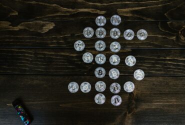 Flat lay of Bitcoin coins arranged in a shape on a wooden surface representing digital currency.