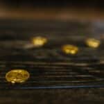 Close-up of multiple gold Bitcoin coins on a wooden table, representing wealth and cryptocurrency.