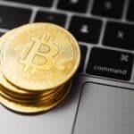 Close-up of gold bitcoin coins on a laptop keyboard, symbolizing digital currency and technology.