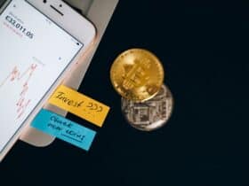 Bitcoin coins and smartphone displaying price chart with investment notes.