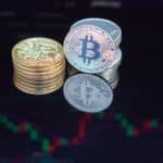 Close-up of bitcoin coins reflecting on a screen with financial market data, highlighting digital currency trend.