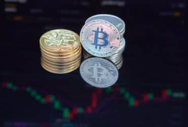 Close-up of bitcoin coins reflecting on a screen with financial market data, highlighting digital currency trend.