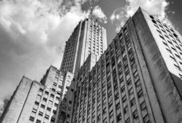 A captivating black and white photo of a skyscraper with a cloudy sky backdrop.