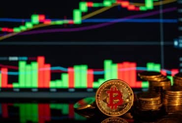 Close-up of Bitcoin coins against a rising financial graph, showcasing cryptocurrency market trends.