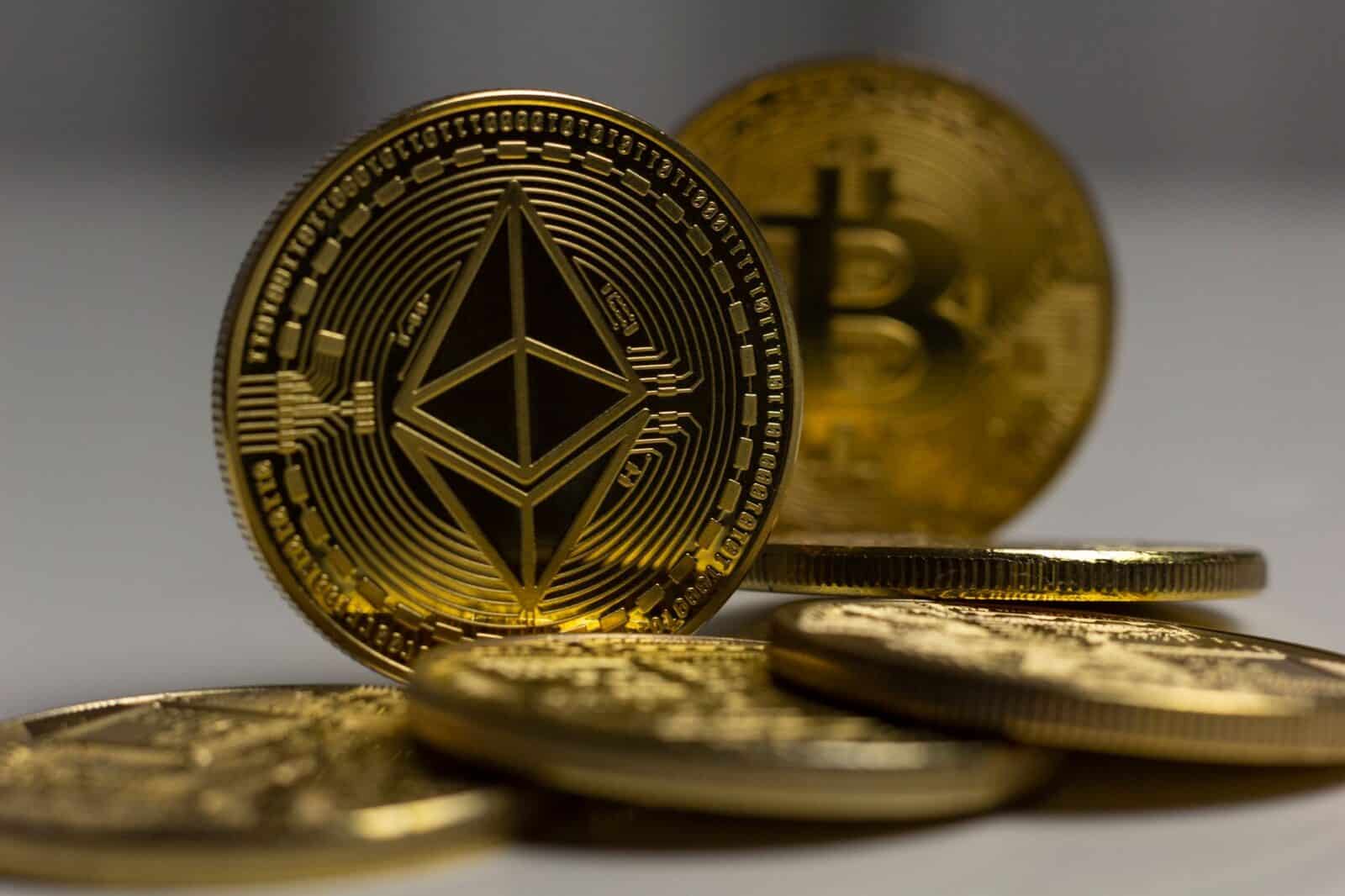 Detailed close-up shot of Ethereum and Bitcoin gold coins with a blurred background, signifying cryptocurrency.