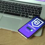 Smartphone displaying blockchain application resting on a laptop, symbolizing modern technology and finance.