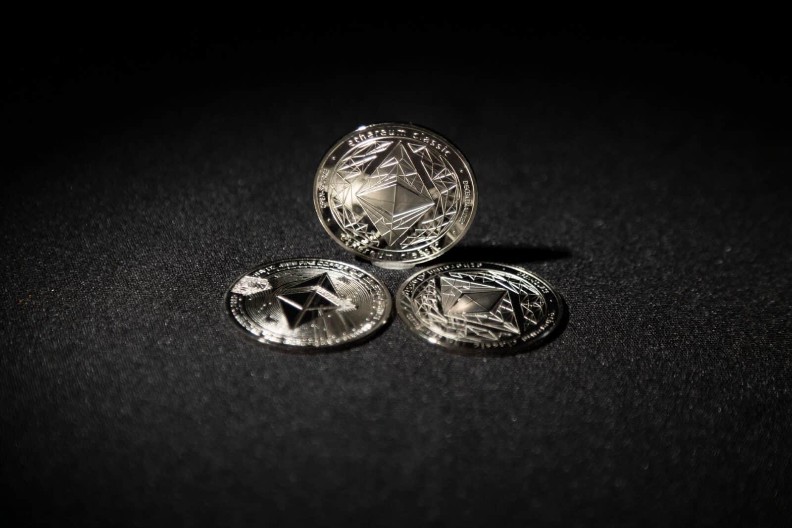Close-up of three Ethereum coins on a dark background, showcasing digital currency themes.