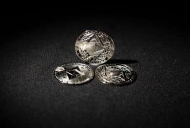 Close-up of three Ethereum coins on a dark background, showcasing digital currency themes.