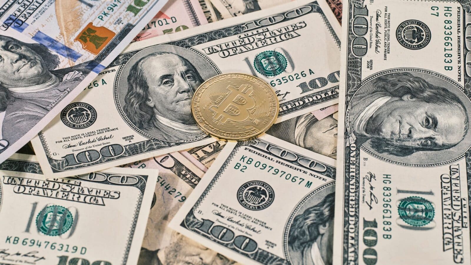 Bitcoin coin placed on scattered US dollar bills, representing cryptocurrency and finance.