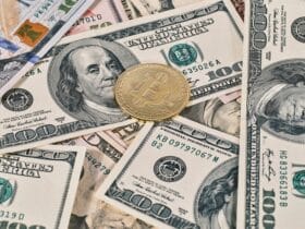 Bitcoin coin placed on scattered US dollar bills, representing cryptocurrency and finance.