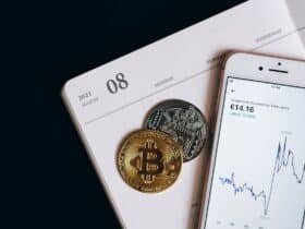 A smartphone displays cryptocurrency data alongside Bitcoin and Ethereum coins on an August calendar.
