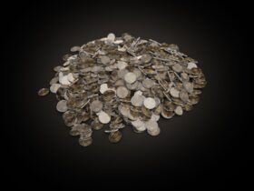A large pile of assorted coins on a dark black background, symbolizing wealth and finance.