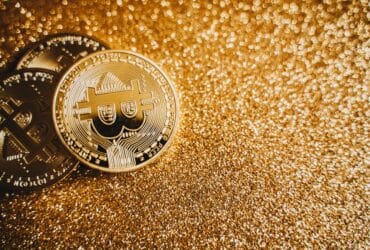 Close-up of bitcoins on a shimmering gold background, symbolizing digital wealth and investment.