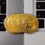 Close-up of Bitcoin coins resting on two laptop keyboards, representing digital currency and technology.
