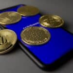 Five cryptocurrency coins displayed on a smartphone with Coinbase app open.