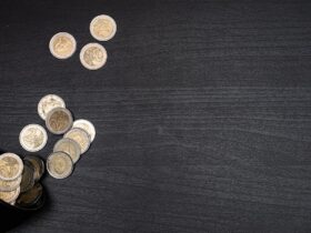 A collection of euro coins scattered on a dark textured surface, with space for text.