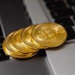 Close-up of golden bitcoins on a laptop keyboard representing digital currency and wealth.