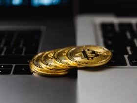 Close-up of gold Bitcoin coins placed on laptop keyboards, representing digital currency and wealth.
