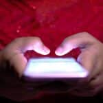 Close-up van handen die een cryptoadres intypen op een smartphone