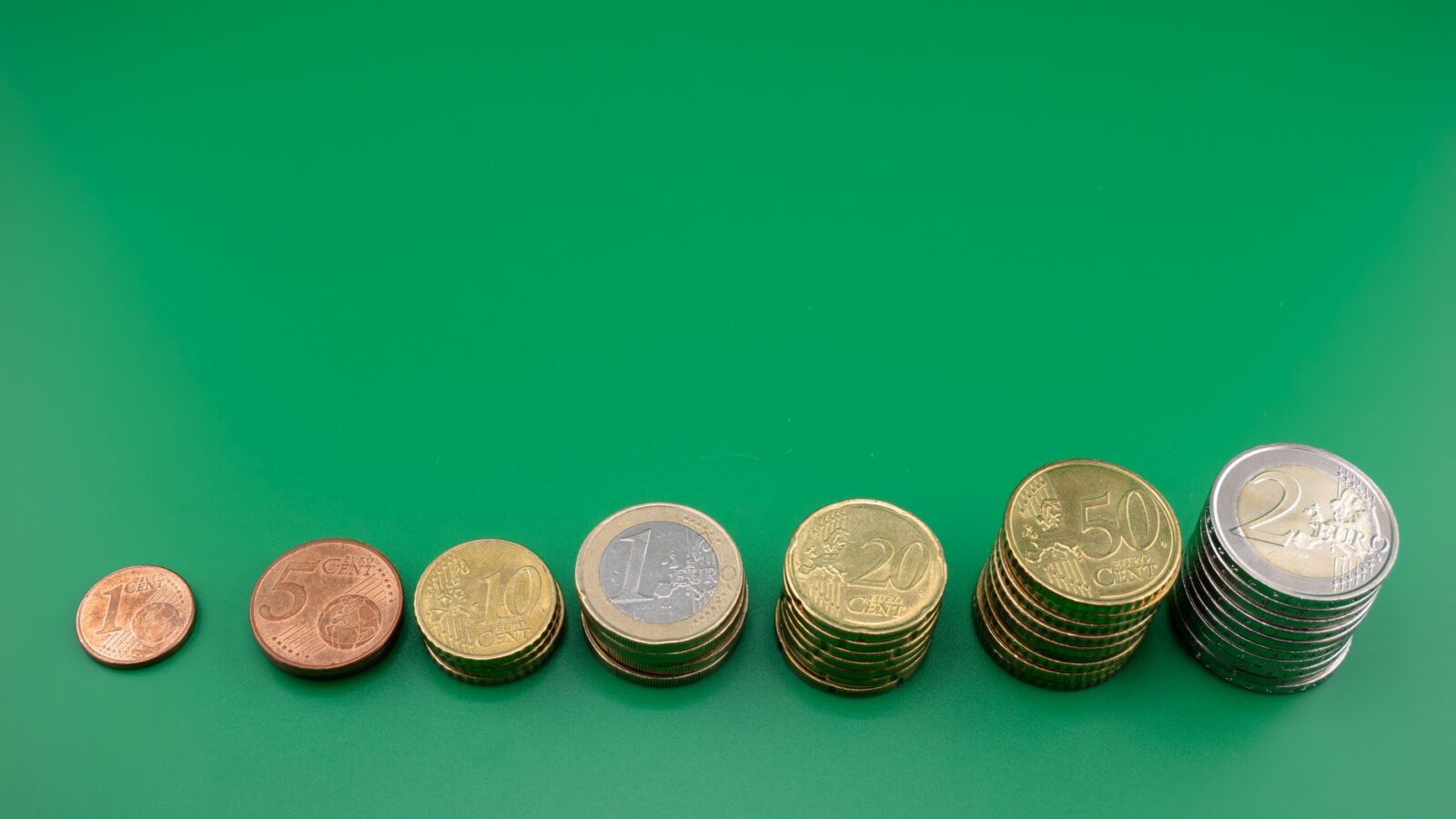 Various euro coins stacked incrementally on a vibrant green background.