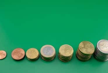 Various euro coins stacked incrementally on a vibrant green background.