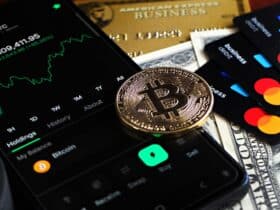 Bitcoin coin with financial data, credit cards, and currency on a desk.