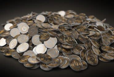 A close-up view of a large pile of gold and silver cryptocurrency coins indicating financial wealth.