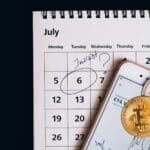 Smartphone with bitcoins on calendar, marking investment date.
