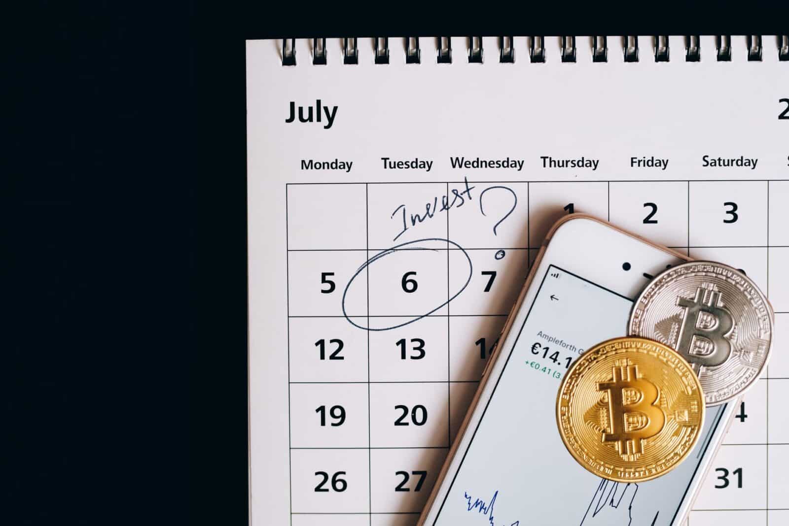 Smartphone with bitcoins on calendar, marking investment date.