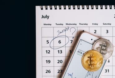 Smartphone with bitcoins on calendar, marking investment date.