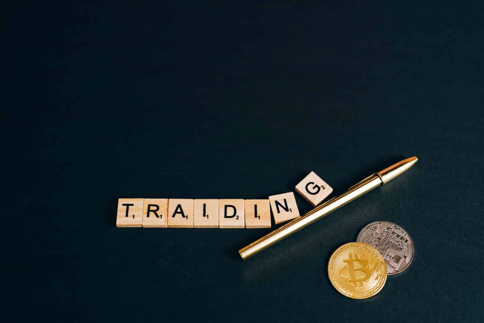 Bitcoin and trading concept shown with coins, pen, and letter tiles on a dark background.