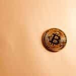 Close-up of a Bitcoin coin on a soft, neutral background representing the digital currency concept.