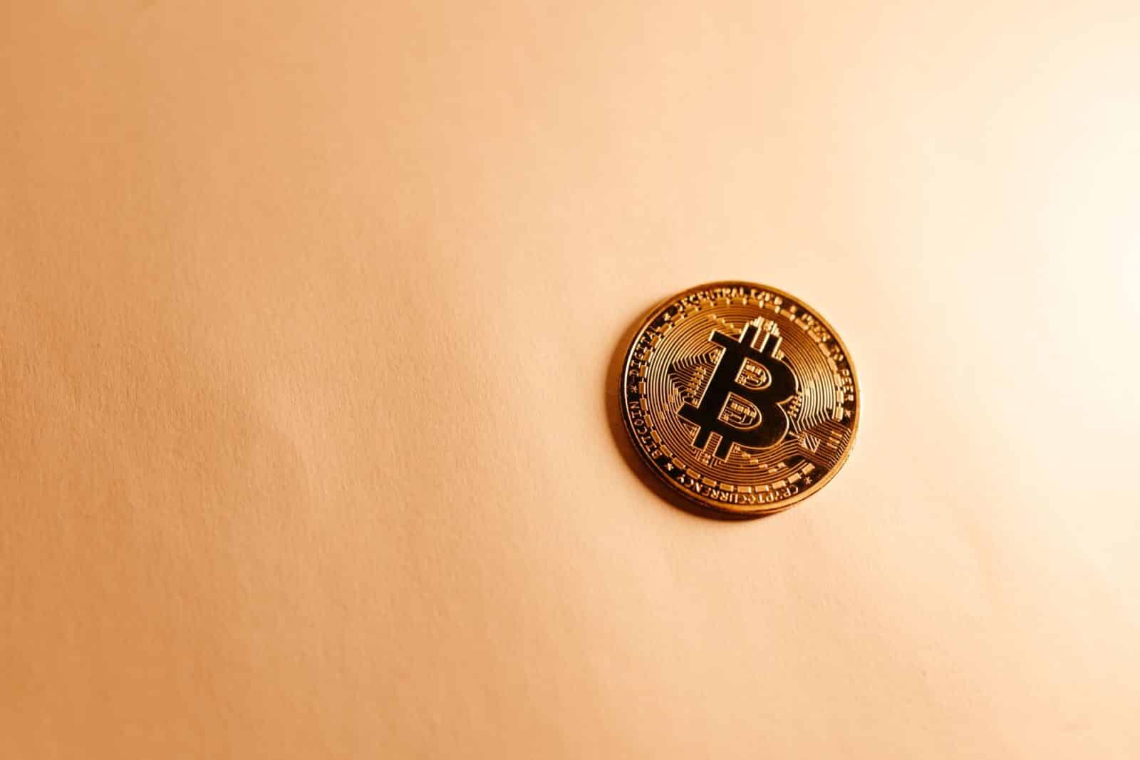 Close-up of a Bitcoin coin on a soft, neutral background representing the digital currency concept.
