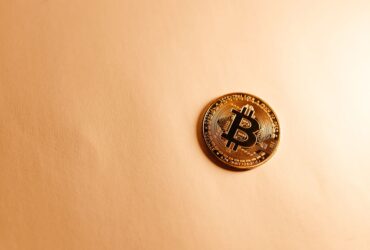 Close-up of a Bitcoin coin on a soft, neutral background representing the digital currency concept.