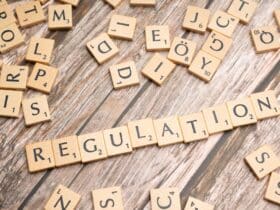 Wooden letter tiles spelling 'Regulation' on a textured wood background, conveying themes of compliance and structure.