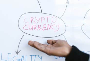 Close-up of a hand gesturing at a cryptocurrency diagram on a whiteboard, highlighting crypto concepts.