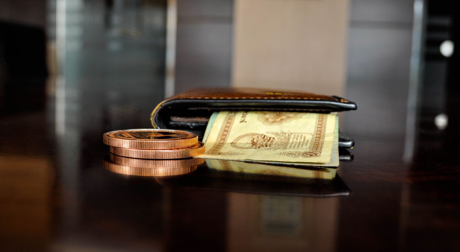 Arrangement of antique coins and banknotes beside a wallet, reflecting luxury finance.
